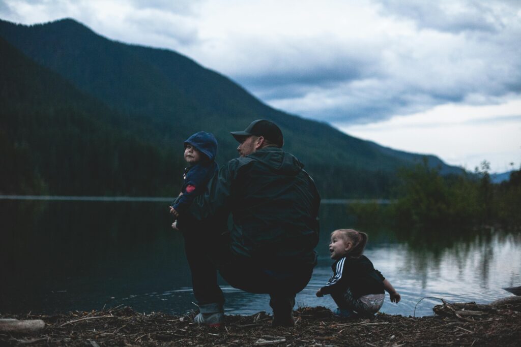 A father spending quality time with his two children by a lake.